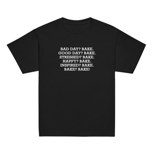 "Bad Day? Bake. Good Day? Bake. Stressed? Bake. Happy? Bake. Inspired? Bake. Bake? Bake!" printed on a black youth classic tee laying on a flat surface