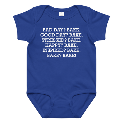 "Bad Day? Bake. Good Day? Bake. Stressed? Bake. Happy? Bake. Inspired? Bake. Bake? Bake!" printed on a royal baby jersey bodysuit laying on a flat surface amongst other clothes