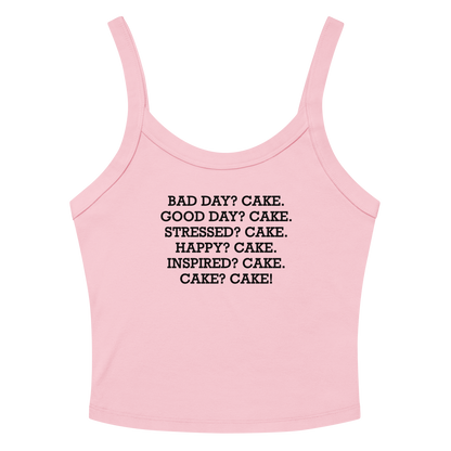 "Bad Day? Cake. Good Day? Cake. Stressed? Cake. Happy? Cake. Inspired? Cake. Cake? Cake!" printed on a solid pink blend women's micro-rib tanktop laying on a flat surface amongst sunglasses and shorts