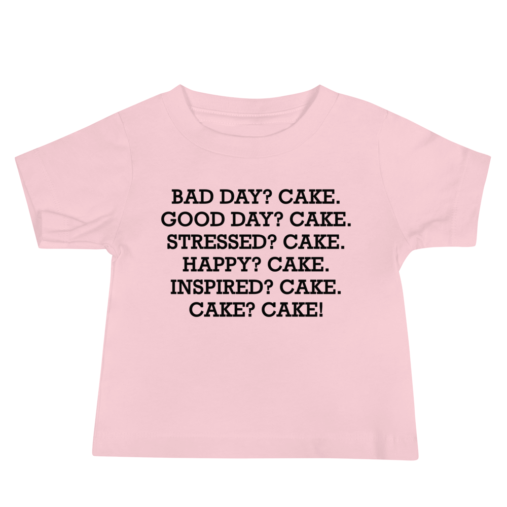 "Bad Day? Cake. Good Day? Cake. Stressed? Cake. Happy? Cake. Inspired? Cake. Cake? Cake!" printed on a pink baby jersey short sleeve tee laying on a flat surface
