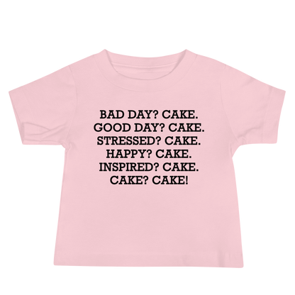 "Bad Day? Cake. Good Day? Cake. Stressed? Cake. Happy? Cake. Inspired? Cake. Cake? Cake!" printed on a pink baby jersey short sleeve tee laying on a flat surface