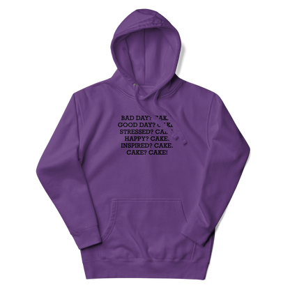 "Bad Day? Cake. Good Day? Cake. Stressed? Cake. Happy? Cake. Inspired? Cake. Cake? Cake!" printed on a purple unisex hoodie laying on a flat surface with the hood up