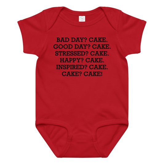 "Bad Day? Cake. Good Day? Cake. Stressed? Cake. Happy? Cake. Inspired? Cake. Cake? Cake!" printed on a red baby jersey bodysuit laying on a flat surface amongst other clothes