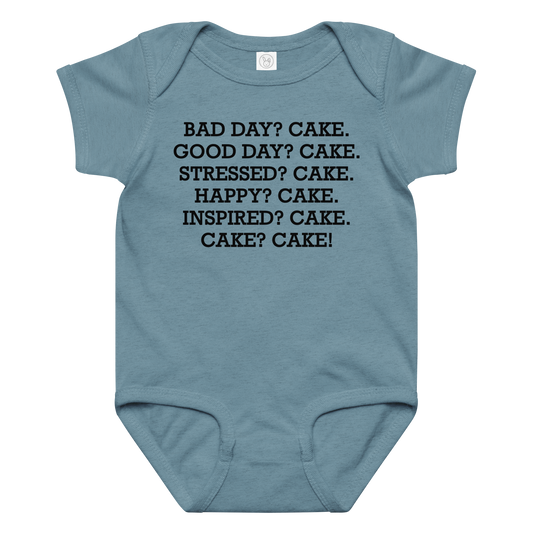 "Bad Day? Cake. Good Day? Cake. Stressed? Cake. Happy? Cake. Inspired? Cake. Cake? Cake!" printed on a vintage indigo baby jersey bodysuit laying on a flat surface amongst other clothes