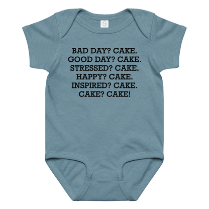 "Bad Day? Cake. Good Day? Cake. Stressed? Cake. Happy? Cake. Inspired? Cake. Cake? Cake!" printed on a vintage indigo baby jersey bodysuit laying on a flat surface amongst other clothes