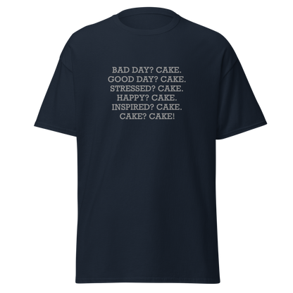 "Bad Day? Cake. Good Day? Cake. Stressed? Cake. Happy? Cake. Inspired? Cake. Cake? Cake!" printed on a navy unisex classic tee laying on a flat surface