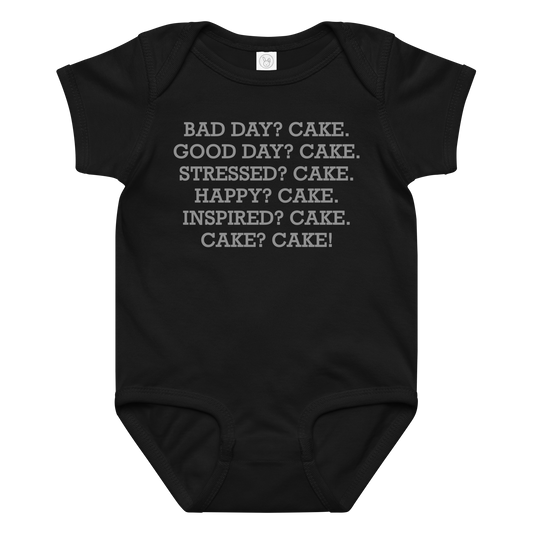 "Bad Day? Cake. Good Day? Cake. Stressed? Cake. Happy? Cake. Inspired? Cake. Cake? Cake!" printed on a black baby jersey bodysuit laying on a flat surface amongst other clothes
