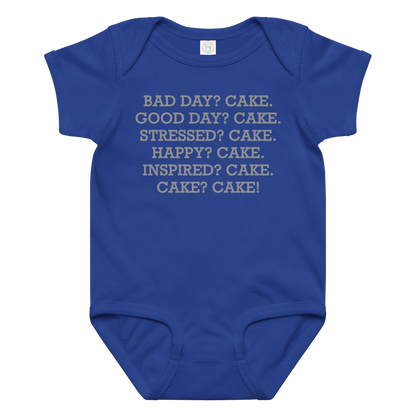 "Bad Day? Cake. Good Day? Cake. Stressed? Cake. Happy? Cake. Inspired? Cake. Cake? Cake!" printed on a royal baby jersey bodysuit laying on a flat surface amongst other clothes