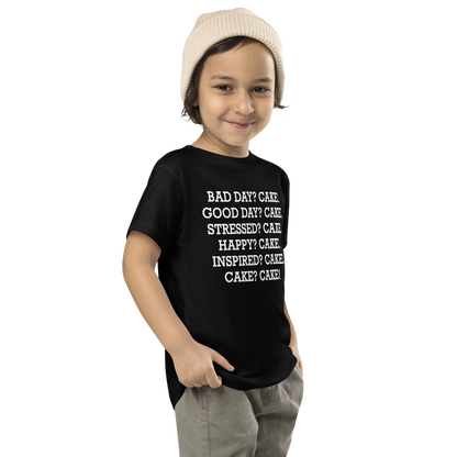 "Bad Day? Cake. Good Day? Cake. Stressed? Cake. Happy? Cake. Inspired? Cake. Cake? Cake!" printed on a black toddler short sleeve tee worn by a male who is also wearing a knit cap