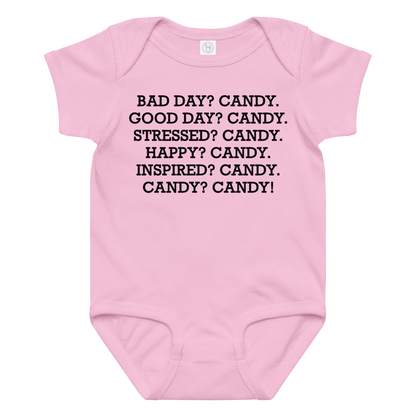 "Bad Day? Candy. Good Day? Candy. Stressed? Candy. Happy? Candy. Inspired? Candy. Candy? Candy!" printed on a pink baby jersey bodysuit laying on a flat surface amongst other clothes