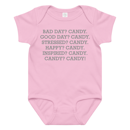 "Bad Day? Candy. Good Day? Candy. Stressed? Candy. Happy? Candy. Inspired? Candy. Candy? Candy!" printed on a pink baby jersey bodysuit laying on a flat surface amongst other clothes