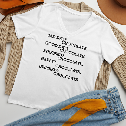 "Bad Day? Chocolate. Good Day? Chocolate. Stressed? Chocolate. Happy? Chocolate. Inspired? Chocolate. Chocolate? Chocolate!" printed on a solid white blend women's relaxed v-neck t-shirt laying on a flat surface amongst other clothes