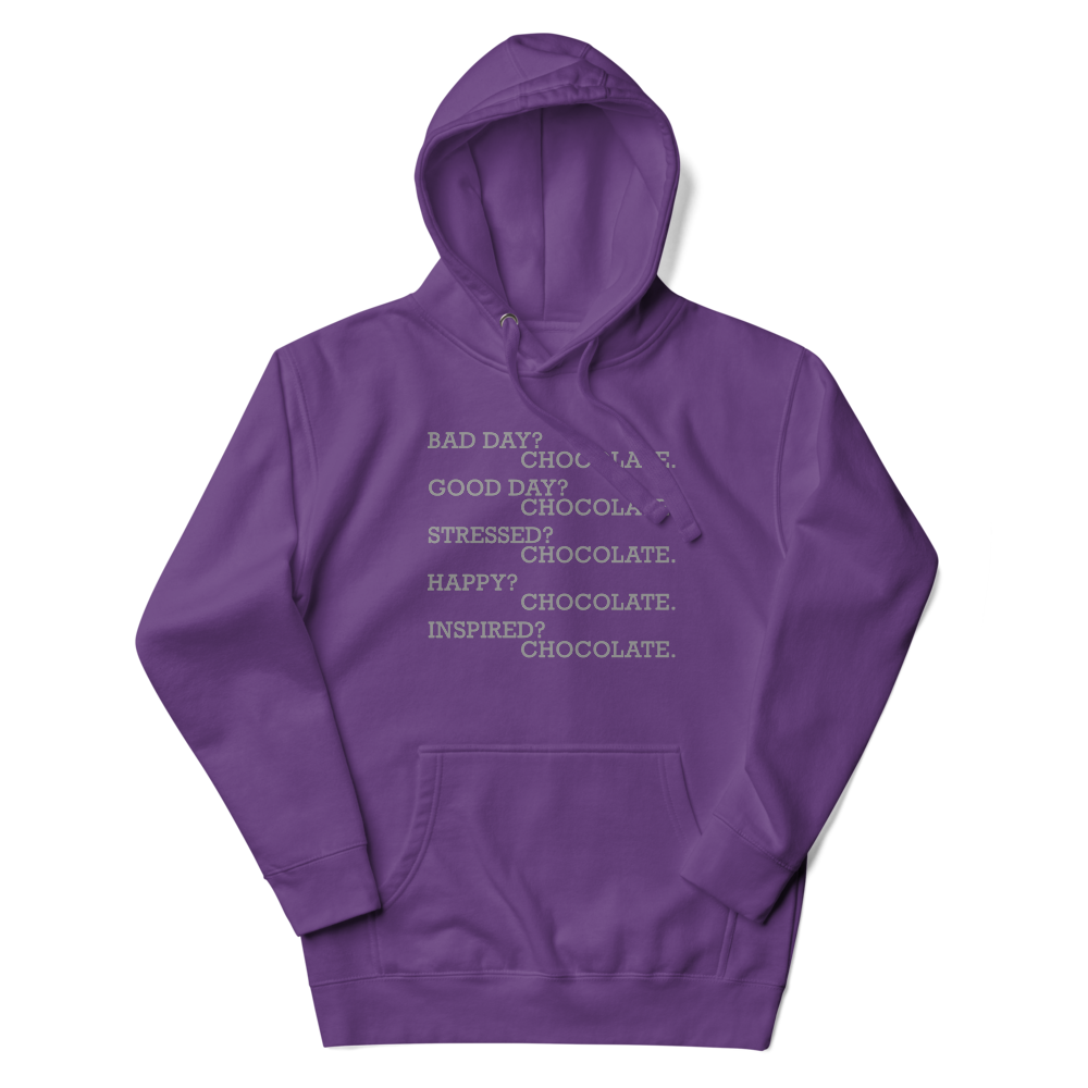 "Bad Day? Chocolate. Good Day? Chocolate. Stressed? Chocolate. Happy? Chocolate. Inspired? Chocolate. Chocolate? Chocolate!" printed on a purple unisex hoodie laying on a flat surface with the hood up