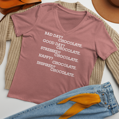 "Bad Day? Chocolate. Good Day? Chocolate. Stressed? Chocolate. Happy? Chocolate. Inspired? Chocolate. Chocolate? Chocolate!" printed on a heather mauve women's relaxed v-neck t-shirt laying on a flat surface amongst other clothes