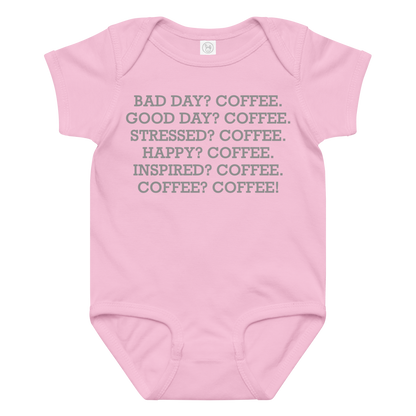 "Bad Day? Coffee. Good Day? Coffee. Stressed? Coffee. Happy? Coffee. Inspired? Coffee. Coffee? Coffee!" printed on a pink baby jersey bodysuit laying on a flat surface amongst other clothes