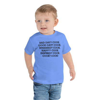 "Bad Day? Cook. Good Day? Cook. Stressed? Cook. Happy? Cook. Inspired? Cook. Cook? Cook!" printed on a heather columbia blue toddler short sleeve tee worn by a male
