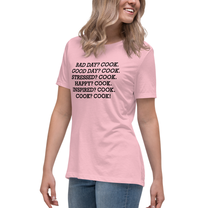 "Bad Day? Cook. Good Day? Cook. Stressed? Cook. Happy? Cook. Inspired? Cook. Cook? Cook!" printed on a pink women's relaxed t-shirt worn by a female