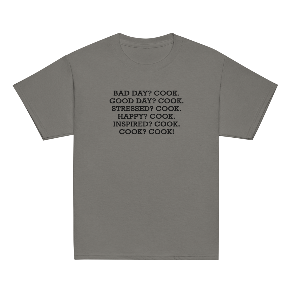 "Bad Day? Cook. Good Day? Cook. Stressed? Cook. Happy? Cook. Inspired? Cook. Cook? Cook!" printed on a charcoal youth classic tee laying on a flat surface