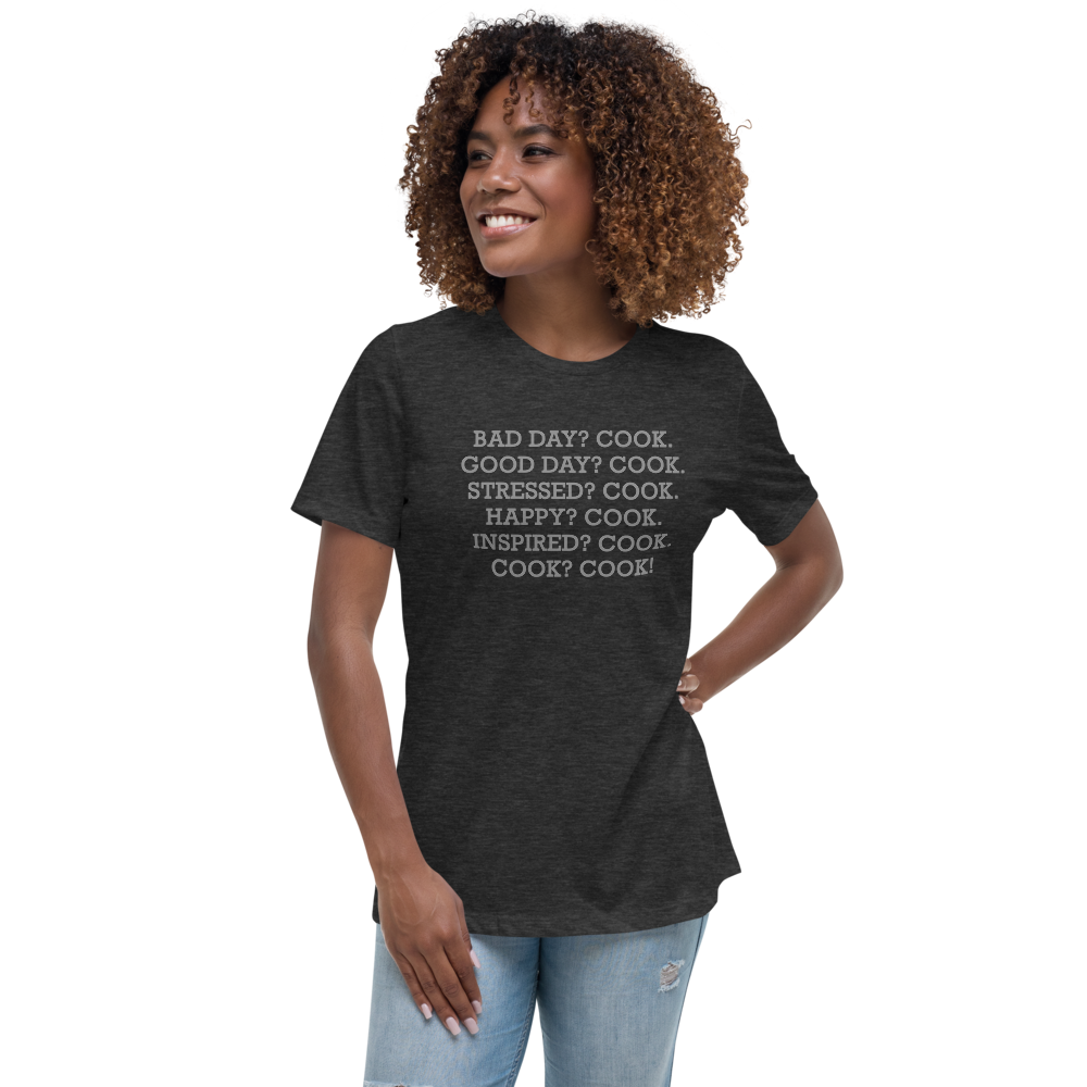 "Bad Day? Cook. Good Day? Cook. Stressed? Cook. Happy? Cook. Inspired? Cook. Cook? Cook!" printed on a dark grey heather women's relaxed t-shirt worn by a female