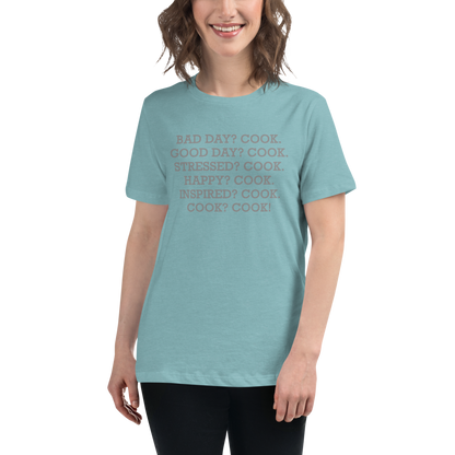 "Bad Day? Cook. Good Day? Cook. Stressed? Cook. Happy? Cook. Inspired? Cook. Cook? Cook!" printed on a heather blue lagoon women's relaxed t-shirt worn by a female
