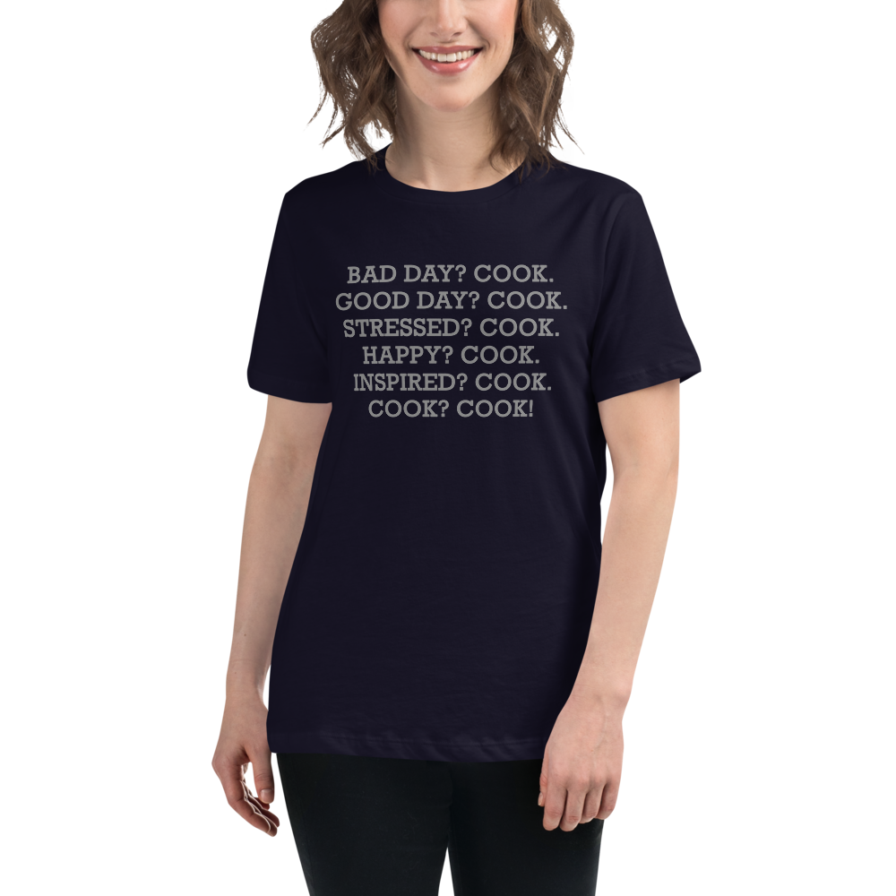 "Bad Day? Cook. Good Day? Cook. Stressed? Cook. Happy? Cook. Inspired? Cook. Cook? Cook!" printed on a navy women's relaxed t-shirt worn by a female