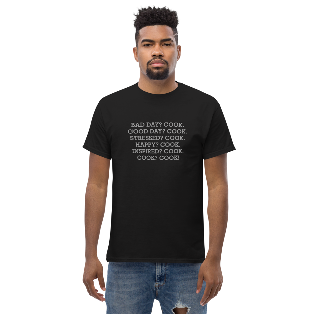 "Bad Day? Cook. Good Day? Cook. Stressed? Cook. Happy? Cook. Inspired? Cook. Cook? Cook!" printed on a black unisex classic tee worn by a male
