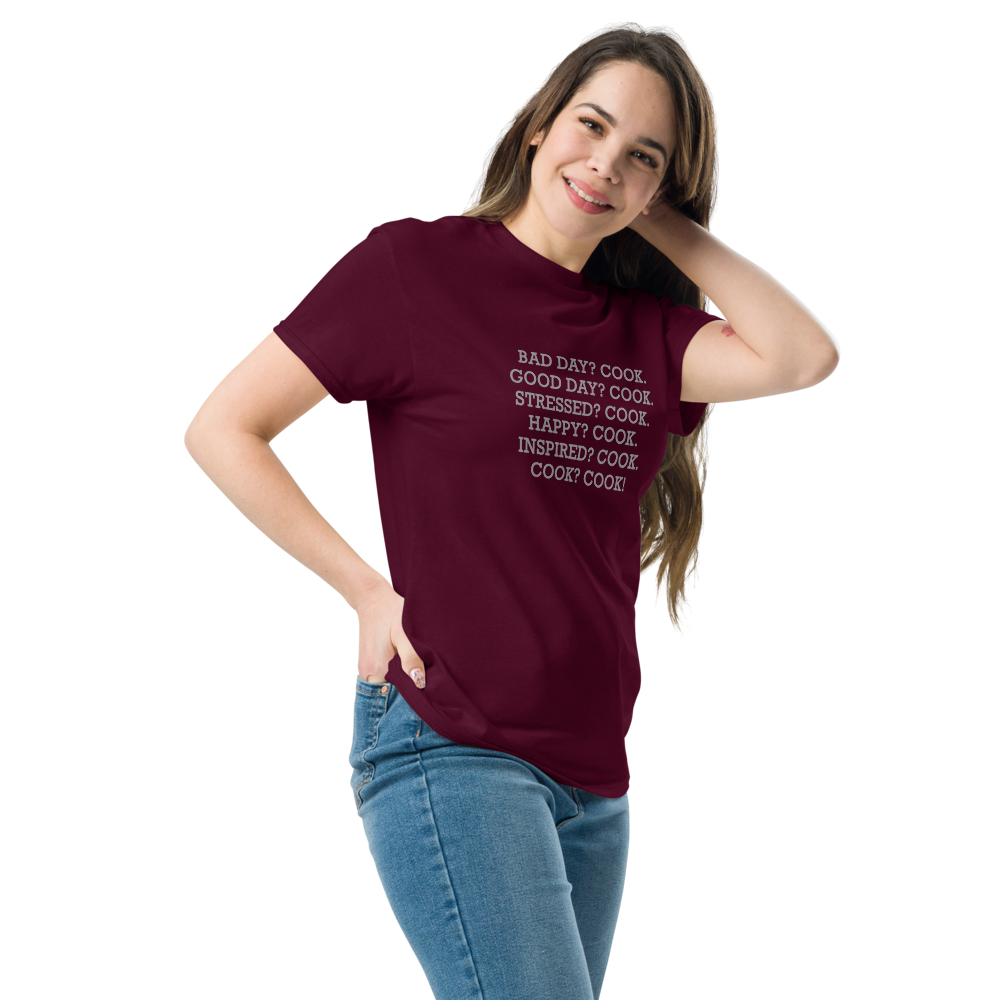 "Bad Day? Cook. Good Day? Cook. Stressed? Cook. Happy? Cook. Inspired? Cook. Cook? Cook!" printed on a maroon unisex classic tee worn by a female