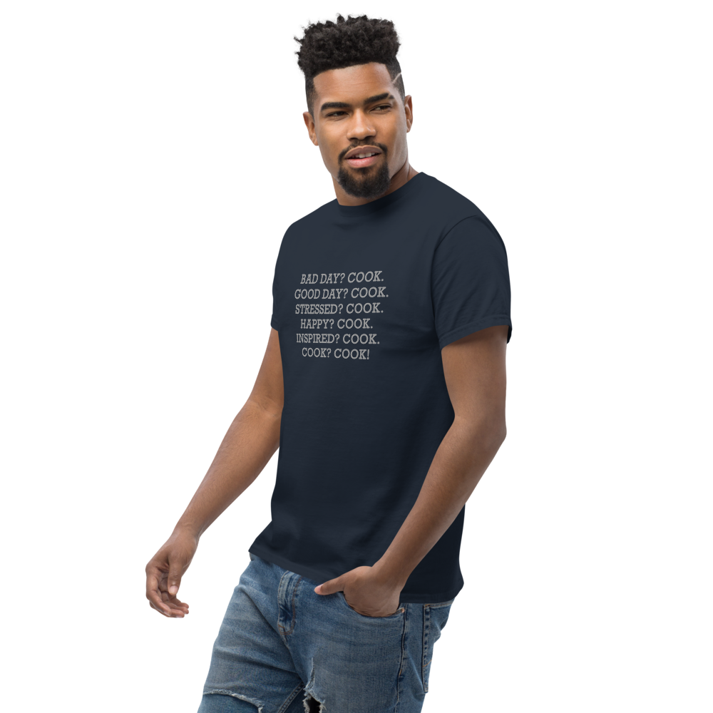 "Bad Day? Cook. Good Day? Cook. Stressed? Cook. Happy? Cook. Inspired? Cook. Cook? Cook!" printed on a navy unisex classic tee worn by a male
