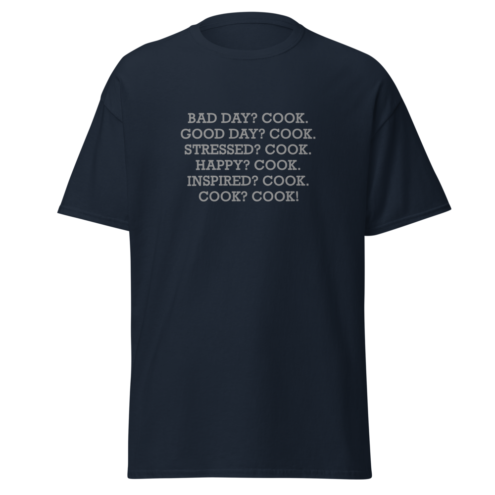 "Bad Day? Cook. Good Day? Cook. Stressed? Cook. Happy? Cook. Inspired? Cook. Cook? Cook!" printed on a navy unisex classic tee laying on a flat surface