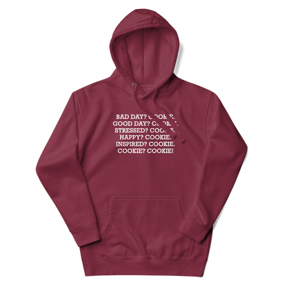 "Bad Day? Cook. Good Day? Cook. Stressed? Cook. Happy? Cook. Inspired? Cook. Cook? Cook!" printed on a maroon unisex hoodie laying on a flat surface with the hood up