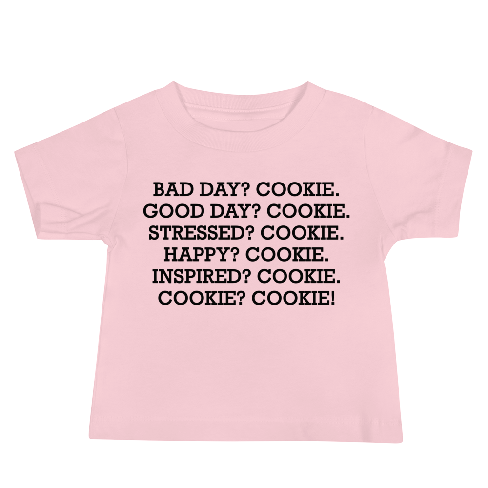 "Bad Day? Cookie. Good Day? Cookie. Stressed? Cookie. Happy? Cookie. Inspired? Cookie. Cookie? Cookie!" printed on a pink baby jersey short sleeve tee laying on a flat surface