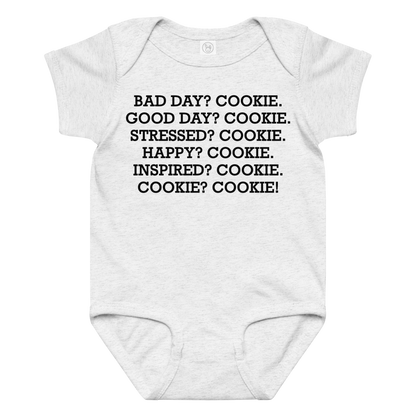 "Bad Day? Cookie. Good Day? Cookie. Stressed? Cookie. Happy? Cookie. Inspired? Cookie. Cookie? Cookie!" printed on a ash baby jersey bodysuit laying on a flat surface amongst other clothes