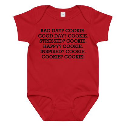 "Bad Day? Cookie. Good Day? Cookie. Stressed? Cookie. Happy? Cookie. Inspired? Cookie. Cookie? Cookie!" printed on a red baby jersey bodysuit laying on a flat surface amongst other clothes