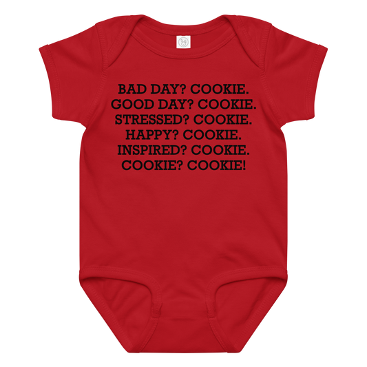 "Bad Day? Cookie. Good Day? Cookie. Stressed? Cookie. Happy? Cookie. Inspired? Cookie. Cookie? Cookie!" printed on a red baby jersey bodysuit laying on a flat surface amongst other clothes