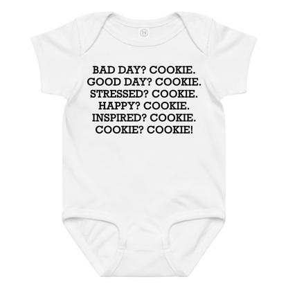 "Bad Day? Cookie. Good Day? Cookie. Stressed? Cookie. Happy? Cookie. Inspired? Cookie. Cookie? Cookie!" printed on a white baby jersey bodysuit laying on a flat surface amongst other clothes