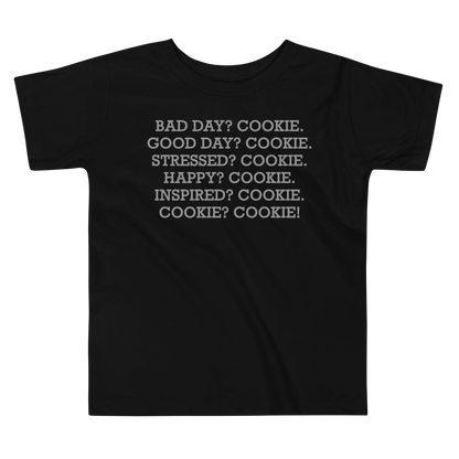 "Bad Day? Cookie. Good Day? Cookie. Stressed? Cookie. Happy? Cookie. Inspired? Cookie. Cookie? Cookie!" printed on a black toddler short sleeve tee laying on a flat surface