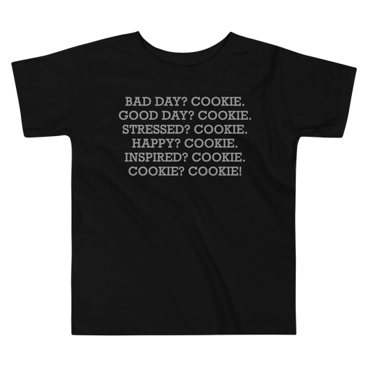 "Bad Day? Cookie. Good Day? Cookie. Stressed? Cookie. Happy? Cookie. Inspired? Cookie. Cookie? Cookie!" printed on a black toddler short sleeve tee laying on a flat surface