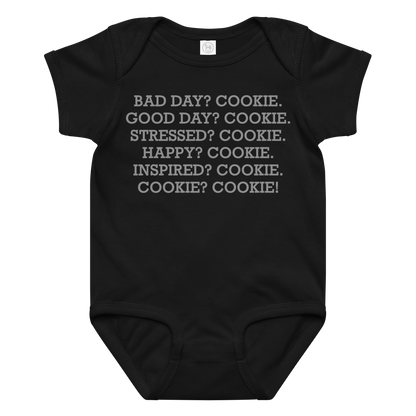 "Bad Day? Cookie. Good Day? Cookie. Stressed? Cookie. Happy? Cookie. Inspired? Cookie. Cookie? Cookie!" printed on a black baby jersey bodysuit laying on a flat surface amongst other clothes