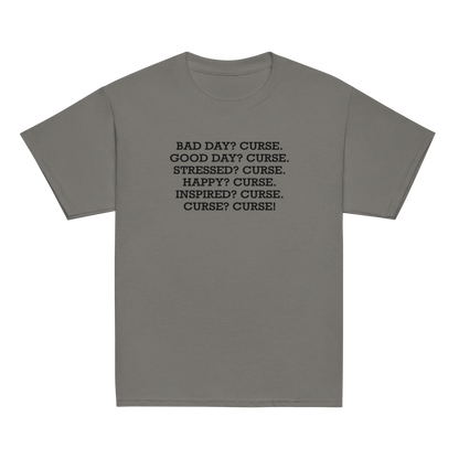 "Bad Day? Curse. Good Day? Curse. Stressed? Curse. Happy? Curse. Inspired? Curse. Curse? Curse!" printed on a charcoal youth classic tee laying on a flat surface