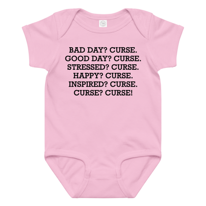 "Bad Day? Curse. Good Day? Curse. Stressed? Curse. Happy? Curse. Inspired? Curse. Curse? Curse!" printed on a pink baby jersey bodysuit laying on a flat surface amongst other clothes