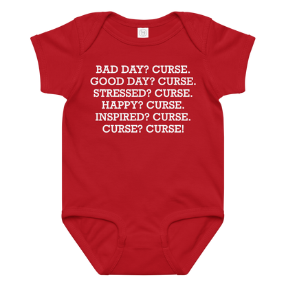 "Bad Day? Curse. Good Day? Curse. Stressed? Curse. Happy? Curse. Inspired? Curse. Curse? Curse!" printed on a red baby jersey bodysuit laying on a flat surface amongst other clothes