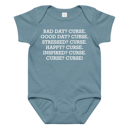 "Bad Day? Curse. Good Day? Curse. Stressed? Curse. Happy? Curse. Inspired? Curse. Curse? Curse!" printed on a vintage indigo baby jersey bodysuit laying on a flat surface amongst other clothes
