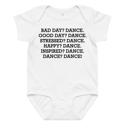 "Bad Day? Dance. Good Day? Dance. Stressed? Dance. Happy? Dance. Inspired? Dance. Dance? Dance!" printed on a white baby jersey bodysuit laying on a flat surface amongst other clothes