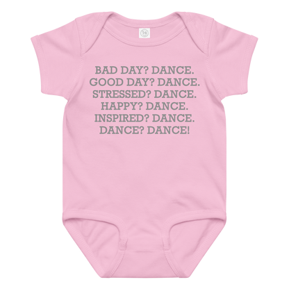 "Bad Day? Dance. Good Day? Dance. Stressed? Dance. Happy? Dance. Inspired? Dance. Dance? Dance!" printed on a pink baby jersey bodysuit laying on a flat surface amongst other clothes