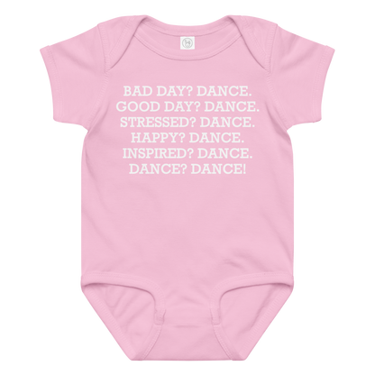 "Bad Day? Dance. Good Day? Dance. Stressed? Dance. Happy? Dance. Inspired? Dance. Dance? Dance!" printed on a pink baby jersey bodysuit laying on a flat surface amongst other clothes