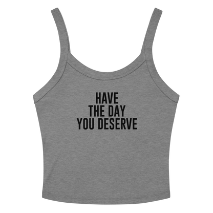 "Have the day you deserve" printed on a athletic heather women's micro-rib tanktop laying on a flat surface amongst sunglasses and shorts
