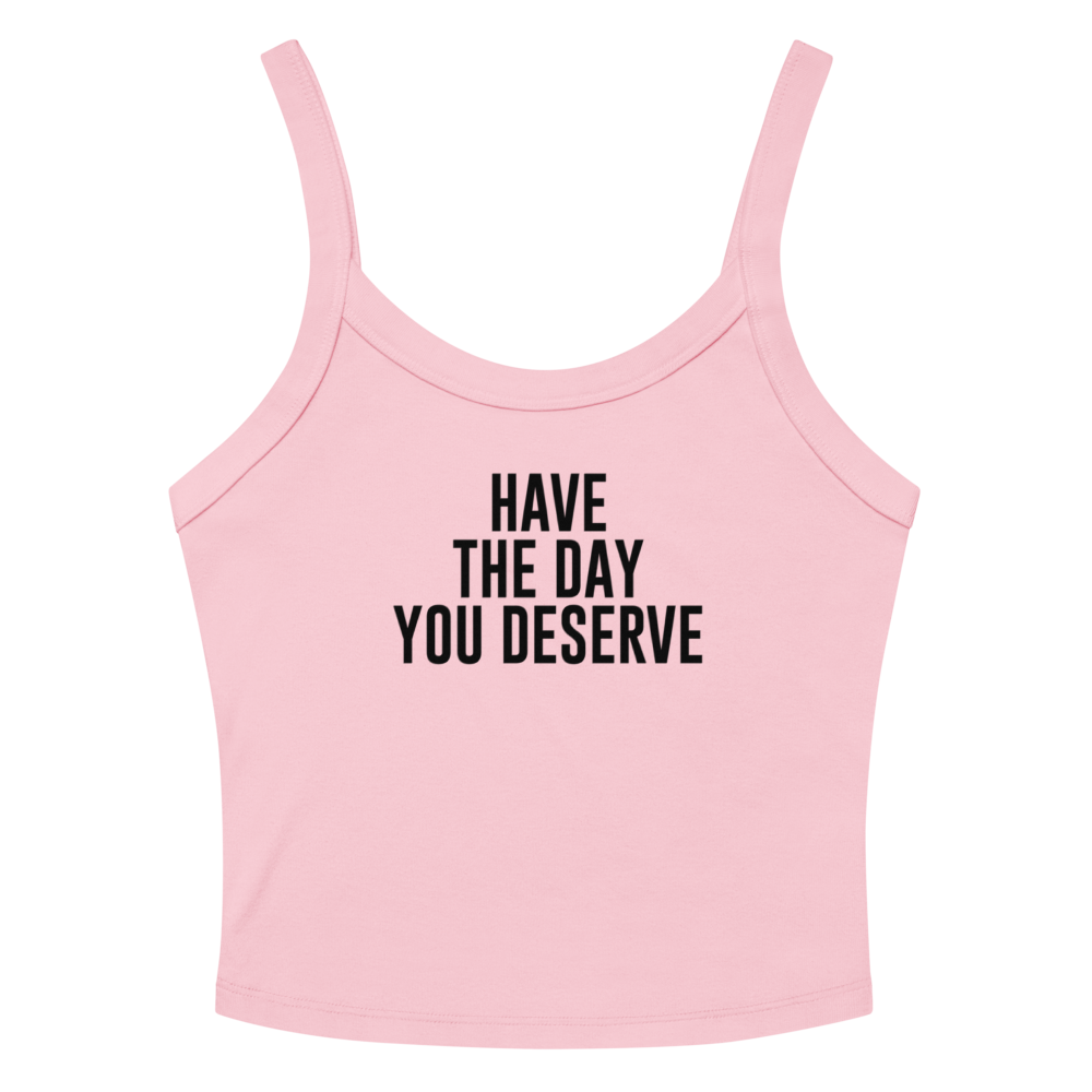 "Have the day you deserve" printed on a solid pink blend women's micro-rib tanktop laying on a flat surface amongst sunglasses and shorts