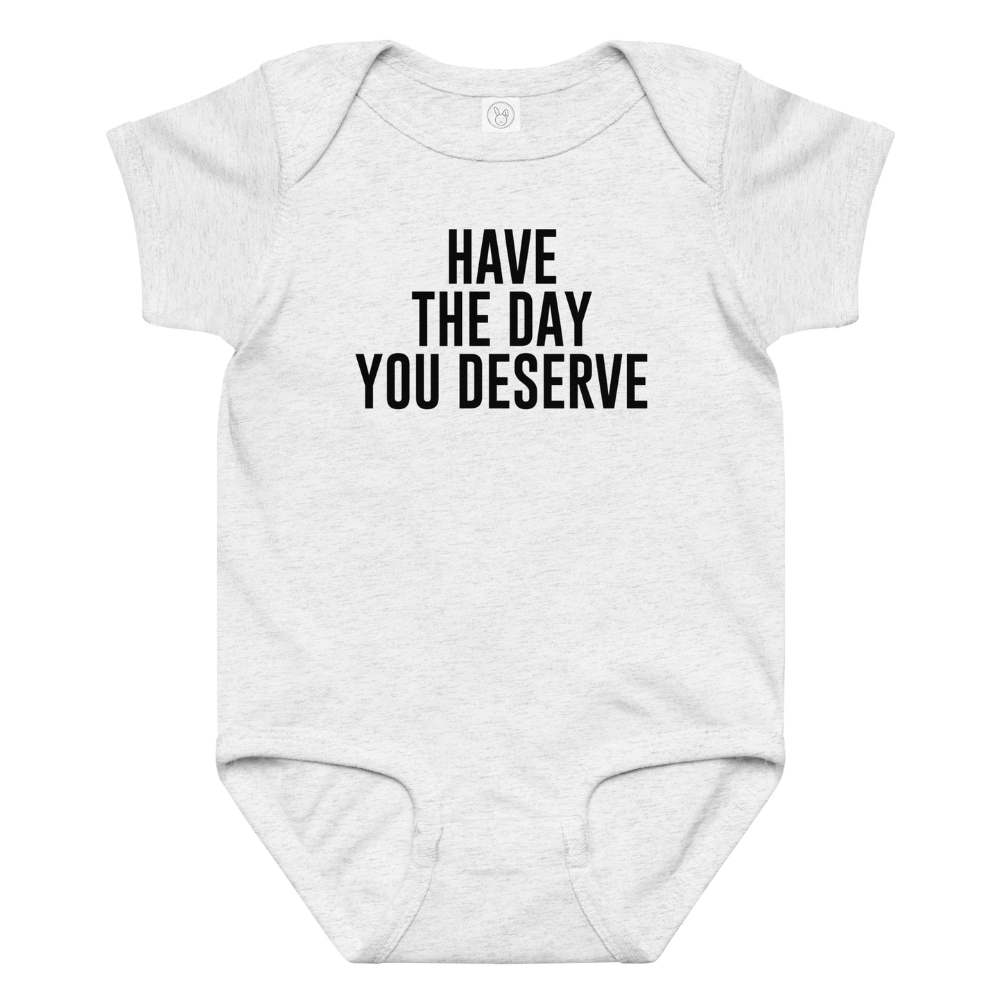 "Have the day you deserve" printed on a ash baby jersey bodysuit laying on a flat surface amongst other clothes