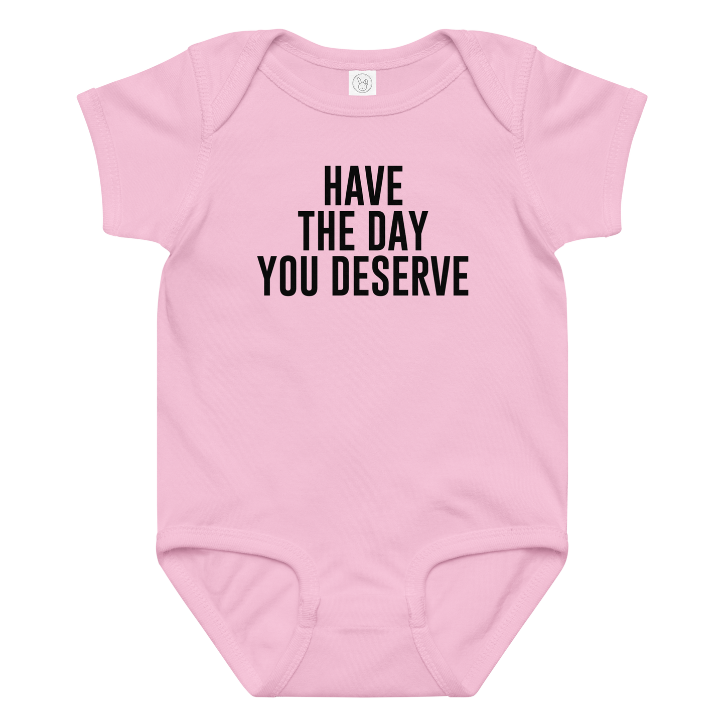 "Have the day you deserve" printed on a pink baby jersey bodysuit laying on a flat surface amongst other clothes