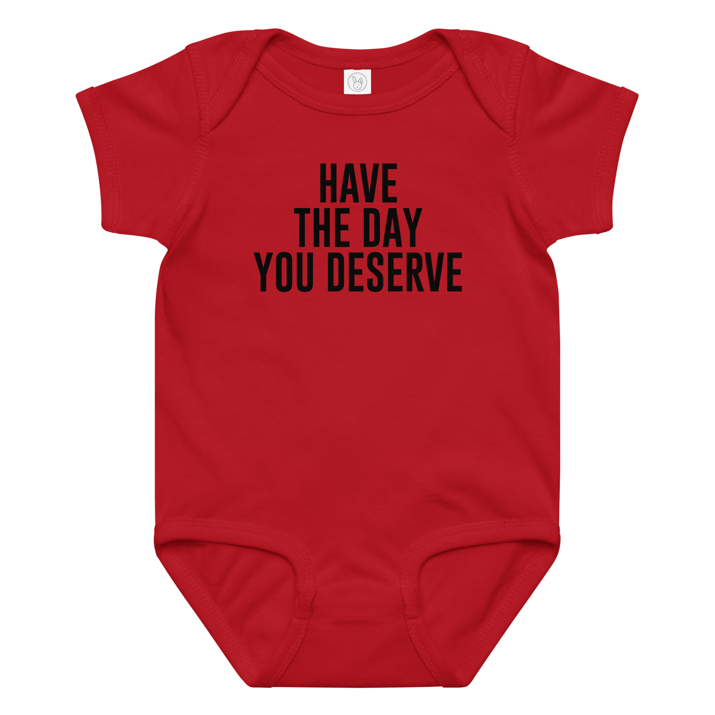 "Have the day you deserve" printed on a red baby jersey bodysuit laying on a flat surface amongst other clothes